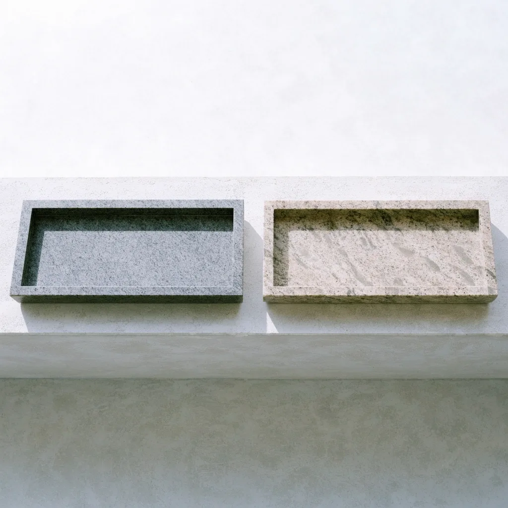 Two empty granite trays of different grain placed side by side on a pale bench